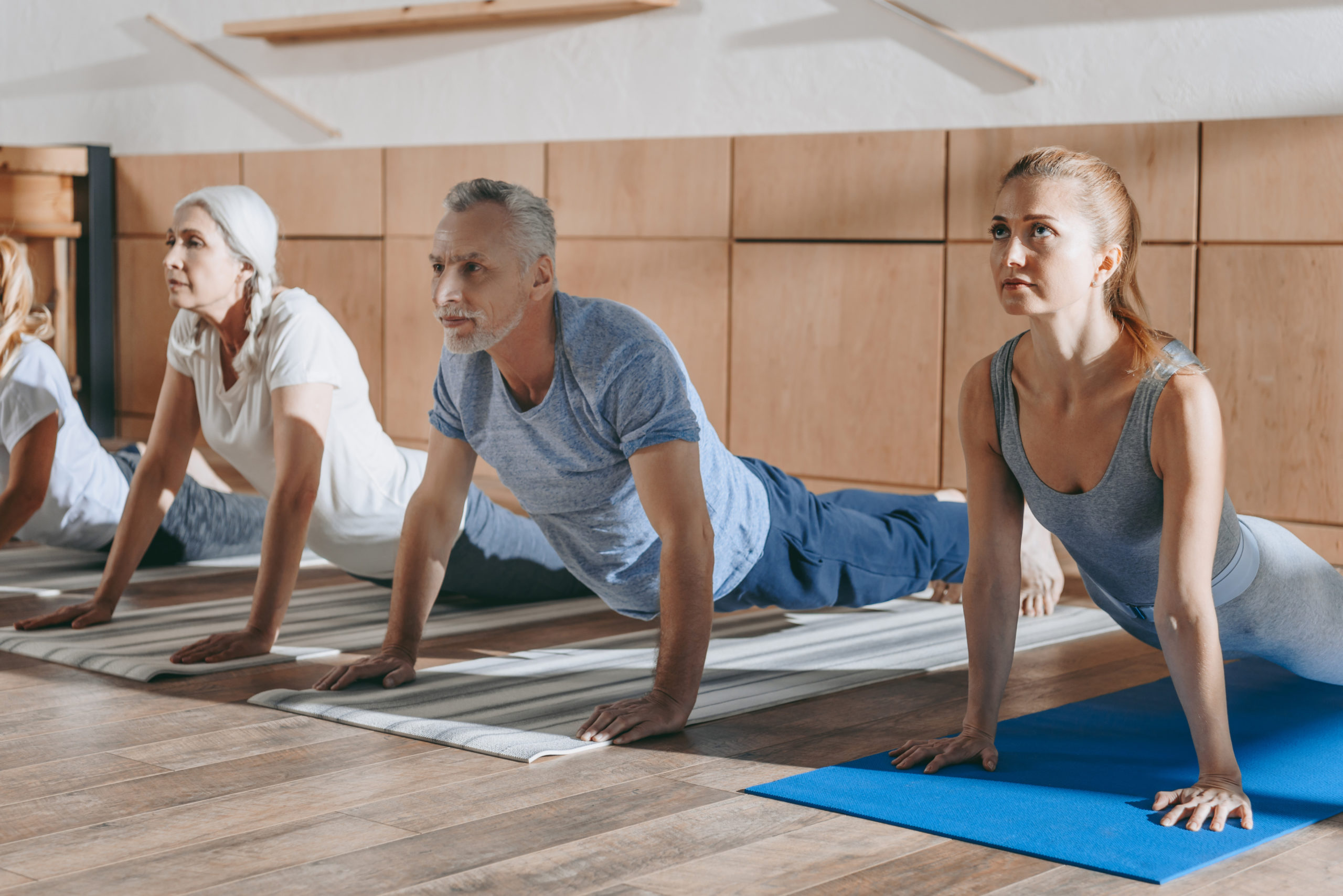 group of senior people practicing yoga in dog pose on mats in studio